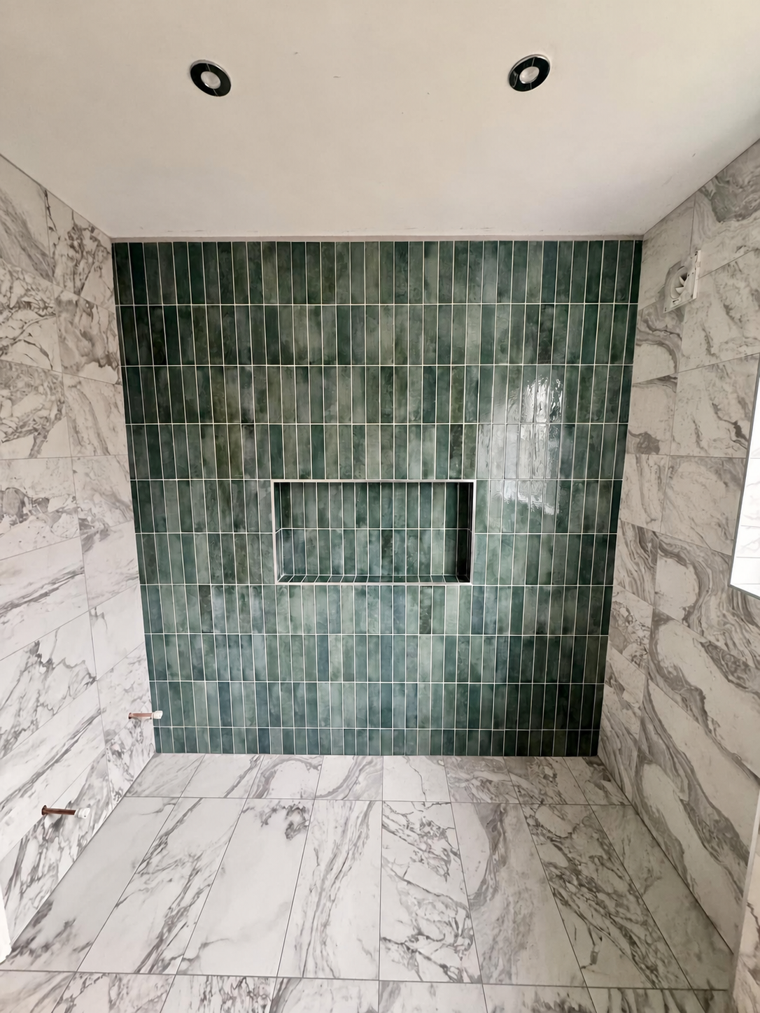 Precision shower tiling with crisp grout lines and tiled niche